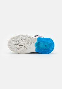 Sola de sapato em borracha branca com uma seção azul translúcida, apresentando uma superfície texturizada e padrões multidimensionais para aderência.