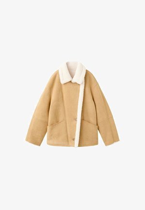 Tan schapenvachtjack met een witte fleece kraag, twee grote voorzakken en een knoopsluiting. Zachte textuur met een ontspannen pasvorm ontwerp.