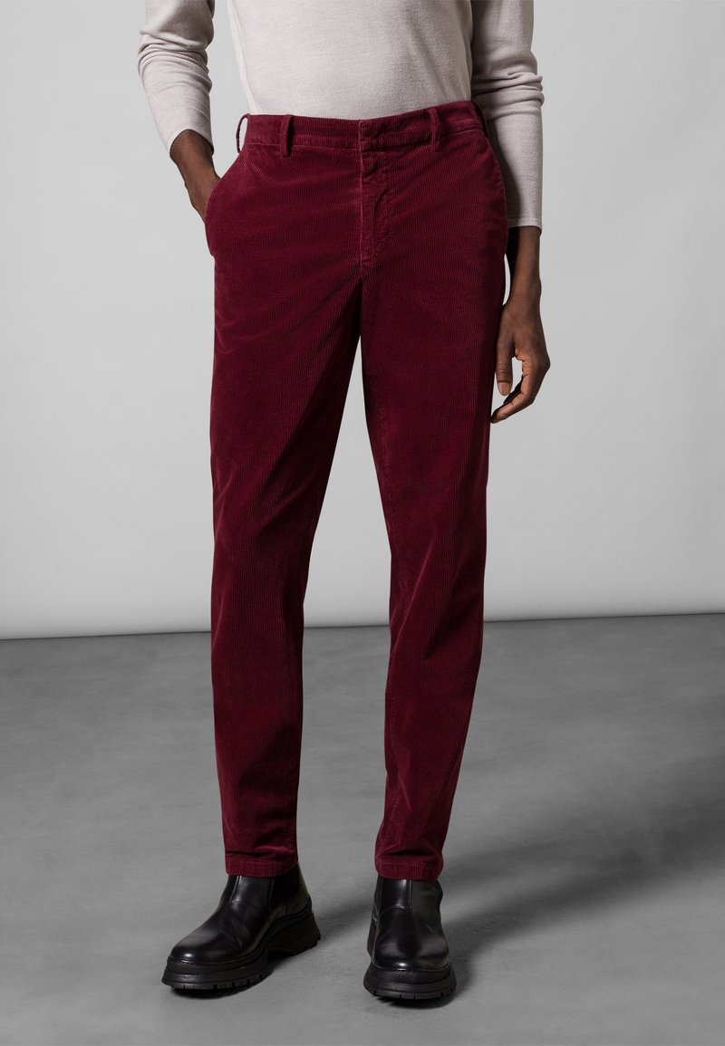 Manšestrové kalhoty v barvě vínové s rovný střihem, s předními kapsami, poutky na pásek a jemnou texturou, kombinované s černými kotníkovými botami.