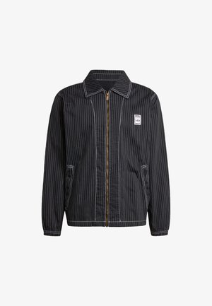 Mustriga musta jakk, mis on valmistatud kangast, esiotsas tõmblukuga, terava krae ja kahe küljetaskuga, rinnale kinnitatud väikese logoplaadiga.