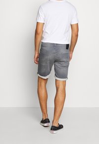 Shorts in denim grigio con risvolti, tasche posteriori e etichetta nera. Accoppiati con una t-shirt bianca semplice e sneakers nere.