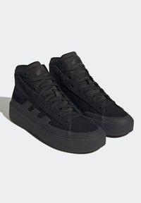 Černé kotníkové tenisky s texturovaným látkovým svrškem, tónovanými tkaničkami, gumovými podrážkami a výrazným logem značky na jazyku a boku.