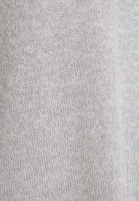 Tissu tricoté gris clair avec une texture fine, présentant un motif zigzag subtil sur toute la surface. Idéal pour la confection de vêtements ou d'accessoires.