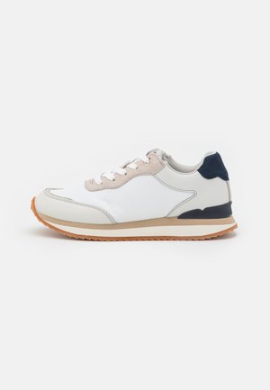 Witte sneaker met een glad leren bovenwerk, beige accenten, een marineblauwe hiel en een gestructureerde rubberen zool. Voorzien van ronde veters en een laag profiel ontwerp.
