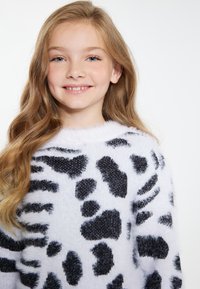 Maglione bianco soffice con motivo animalier nero. Presenta un collo rotondo e una superficie lavorata con un aspetto morbido e accogliente.