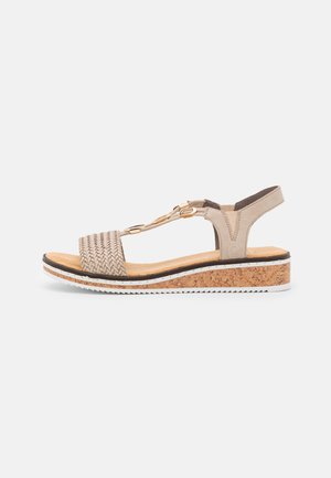 Sandale compensée beige avec semelle en liège, bride avant tissée, accents métalliques dorés et bride arrière réglable pour un maintien sécurisé.