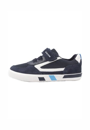 Zapatilla azul y blanca con correa de velcro, materiales de gamuza y malla, punta redondeada y suela de goma con acentos diagonales.