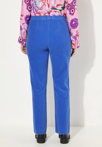 Blå kordflöjelsbyxor med rak ben, en slät textur, elastisk midja och subtila sömnadsdetaljer, i kombination med svarta skor.