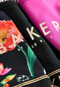 Crno blago s cvetnim oblikovanjm, roza blago, oba s zlatnim napisom: "BAKER" od Ted Baker, naglašeno z zlatnim obrobom.