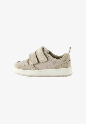 Baskets à velcro beige avec une tige en cuir lisse, des accents en daim et une semelle en caoutchouc texturé. Design minimalist avec un bout arrondi.