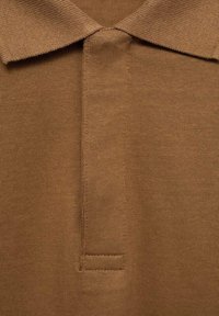 Hnědý polo tričko vyrobené z žebrované tkaniny s límečkem a knoflíkovou légou. Texturovaný povrch a decentní švy.