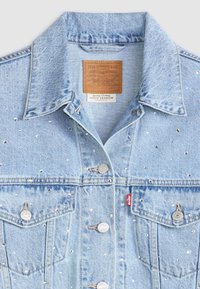 Světle modrá džínsová bunda s rhinestones, má špičatý límec, stříbrné kovové knoflíky a dvě náprsní kapsy. Viditelná nášivka s logem Levi's.