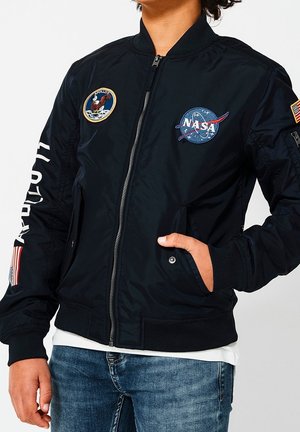 Zwarte bomberjack van nylon, met NASA- en Apollo-missiesymbolen, een ritssluiting en geribde manchetten en zoom. Twee zijzakken.