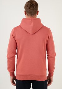 Sudadera con capucha, color coral, mezcla de algodón, puños y dobladillo acanalados, textura suave, longitud media, diseño sencillo sin patrones ni acentos.