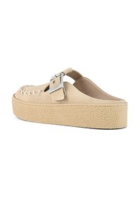 Beige suede clogs with a strap and silver buckle, featuring a textured platform sole for added grip and support.