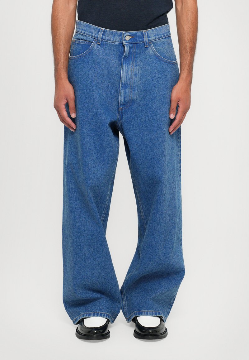 Blå denimbyxor med vida ben och hög midja, med fem fickor och knappstängning. Tyget har en blekt tvätt, vilket ger textur.