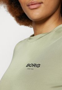 Svijetlozeleni kratkosamostalni majica od glatkog materijala, s crnim "BORG" logotipom i natpisom "SINCE 1956" ispod.