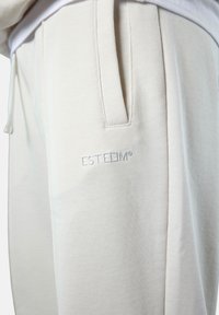 Helle beige Sweatpants aus weichem, strukturiertem Stoff. Mit Seitentaschen und gesticktem Logo am linken Oberschenkel. Elastischer Bund.