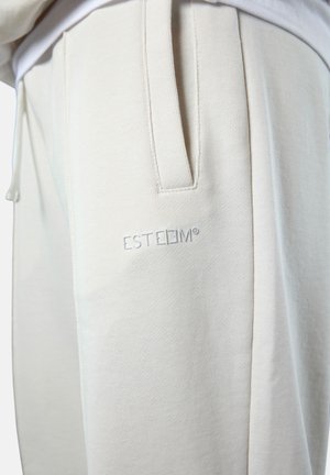Helle beige Sweatpants aus weichem, strukturiertem Stoff. Mit Seitentaschen und gesticktem Logo am linken Oberschenkel. Elastischer Bund.