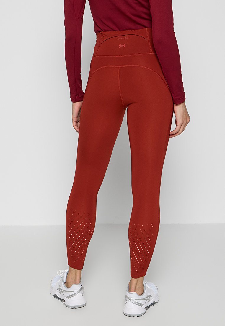 Leggings a vita alta color ruggine con dettagli testurizzati e forature vicino alle caviglie, realizzati in un tessuto elasticizzato traspirante.