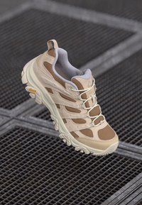 Beige og brune sneakers med en teksturert overdelen og nettingpaneler, snøring og en tykk gummisåle; synlig logo på hælen.