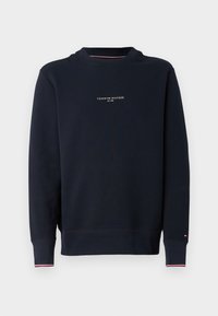 Sweatshirt azul-marinho com decote redondo, apresentando um pequeno texto em branco no peito, punhos canelados e realces em vermelho e branco.