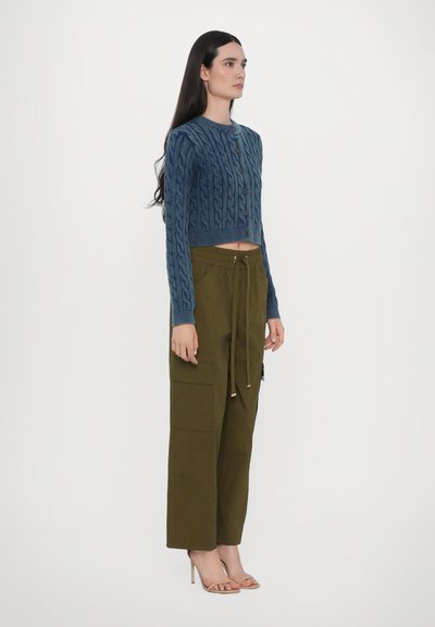 Blå kabelstickad kort cardigan med knappar, parat med olivgröna högmidjade cargobyxor med fickor och dragsko.