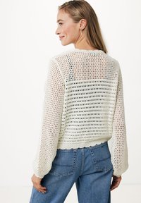 Maglione bianco a maglia con vestibilità loose, tessitura a rete testurizzata, maniche lunghe e lunghezza cropped, abbinato a jeans a vita alta.