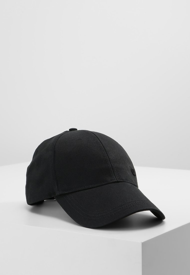 Casquette de baseball en coton noir avec une visière courbée reposant sur une surface blanche sur fond gris clair.