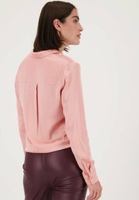  Lichtroze, zijdeachtige blouse met een plooiback en een puntige kraag, met lange mouwen en knoopmanchetten.