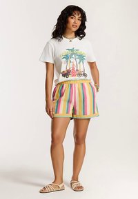 Biele bavlnené tričko s farebnou grafikou palmy, kombinované s viacfarebnými pruhovanými šortkami v žltej, ružovej a modrej farbe, so sťahovacím elastickým pásom.