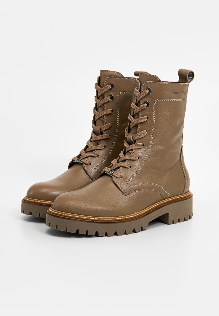 Bottines en cuir marron avec un bout rond, un laçage et une semelle épaisse et robuste comportant un accent de couture visible.
