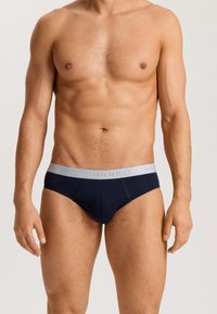 Slip blu navy realizzati in tessuto morbido con una cintura elastica grigia su cui è stampato il marchio "HANRO". Vestibilità sartoriale con cuciture sottili.