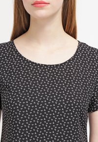 Top negro de manga corta con un sutil patrón floral blanco y un cuello redondo, hecho de una tela suave y transpirable.