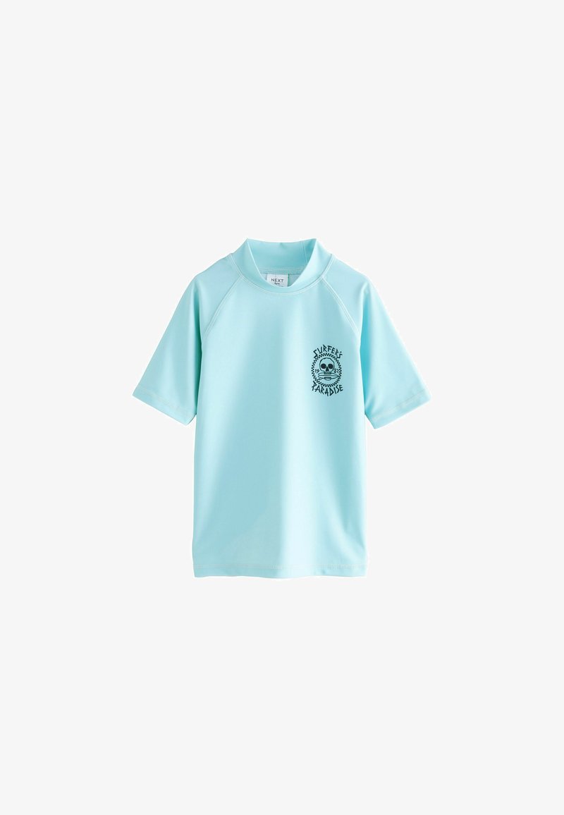 Rash guard de manga corta en azul claro, hecho de una tela suave y elástica. Presenta un gráfico de una calavera negra con el texto "SURFERS PARADISE" en la parte frontal.