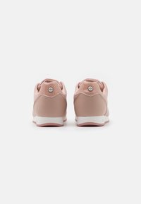 Růžové tenisky s hladkým koženým povrchem, zaobleným tvarem, bílou podešví a kovovým logem na patě.