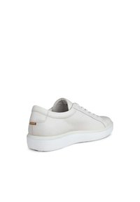 Baskets blanches en cuir avec une finition texturée, dotées d'une semelle en caoutchouc blanche, d'un bout rond et d'un subtil accent beige au talon.