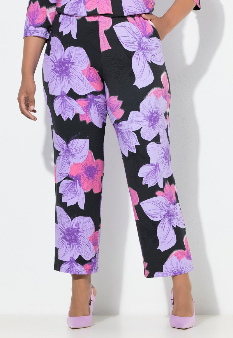 Schwarze Hose mit lebhaftem lila und pinkem Blumenmuster, geradem Bein und Taschen. Kombiniert mit hellrosa Absätzen.