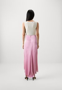 Ribbed white knit-top yhdistettävä pitkän, valuvan vaaleanpunaisen satiinihameen kanssa, jossa on takana napitus ja kevyt laskos. Mustat korkokengät.