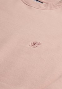 Sweatshirt rosa chiaro con scollatura a girocollo a coste, caratterizzato da un piccolo logo ricamato di una tonalità leggermente più scura. Tessuto morbido e texture.
