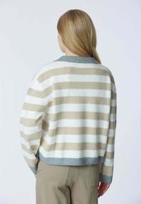 Maglione a righe beige e bianco, con colletto e polsini a coste grigi. Tessuto morbido, vestibilità rilassata con una forma ampia.