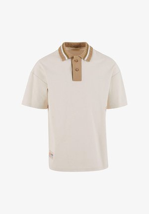 Lyhythihainen polo-paita vaaleanbeigessä värissä, jossa on samalla tekstuurilla varustettu ruskea kaulus, kahdella napilla ja valkoisilla korostusraidoilla kauluksessa.