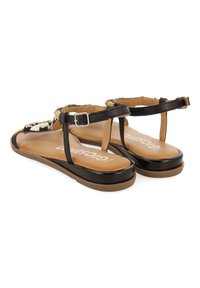 Sandalias negras y beige con diseño de tira en T, embellecidas con acentos texturizados, suela plana y hebilla ajustable en el tobillo.