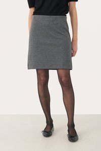 Rockschwarz-weißes Hahnentrittmuster aus strukturiertem Stoff, kombiniert mit durchsichtigen schwarzen Strumpfhosen und Ballerinas. Der Rock ist knielang.