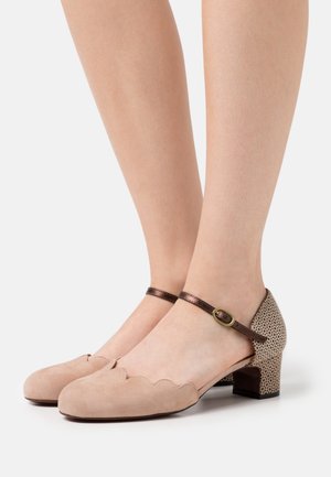 Chaussures en daim beige avec un bord festonné, une bride de cheville marron, et un motif à pois sur le talon. Design à talon carré bas.