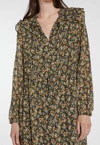 Robe à manches longues noire à imprimé floral, avec un col froncé, des poignets smockés et une taille à cordon pour un ajustement personnalisable.