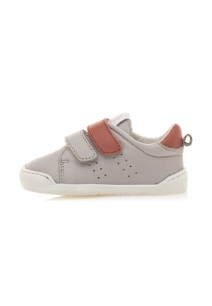 Grijze leren schoen met een rode accentriem, perforaties aan de zijkant, witte rubberen zool en een trekband aan de hiel.