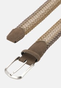 Vävd bälte i beige och bruna nyanser, med en mjuk mockadel och ett silverfärgat metallspänne i rektangulär form.
