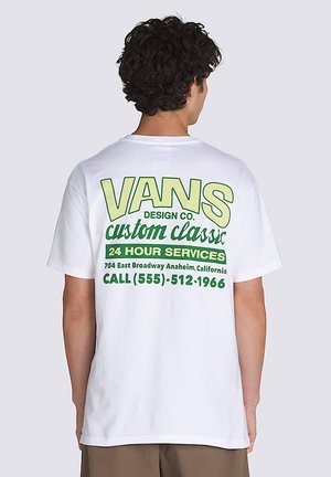 Camiseta blanca de algodón con texto gráfico verde en la parte posterior. El texto incluye "VANS DESIGN CO." y detalles del servicio en varias tamaños de fuente.