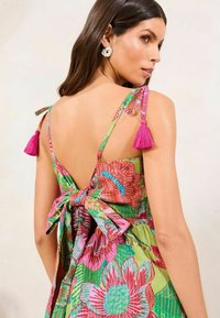 Rochie florală colorată cu bretele subțiri, ciucuri roz și o fundă pe spate. Fabricată dintr-un material ușor, cu un model.